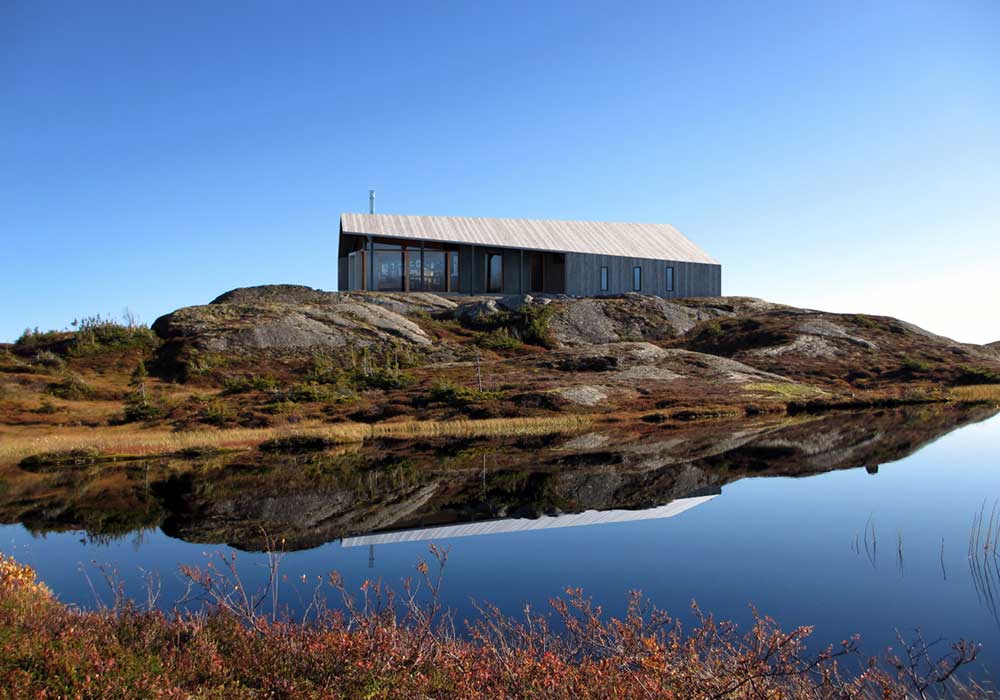 Wooden prefab cabin mirrored in a lake